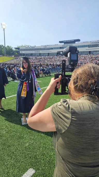 A graduate blowing a kiss to the camera as a photographer takes her picture.