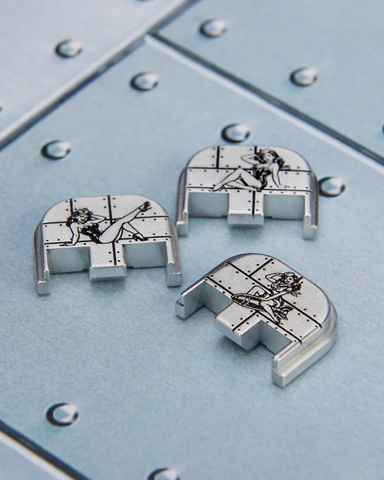 Three engraved aluminum rear plates featuring vintage pin-up girl artwork displayed on a brushed metal surface.