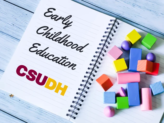 Open notebook with wooden shapes on top of the right side and "Early Childhood Education CSUDH" written on the left side.