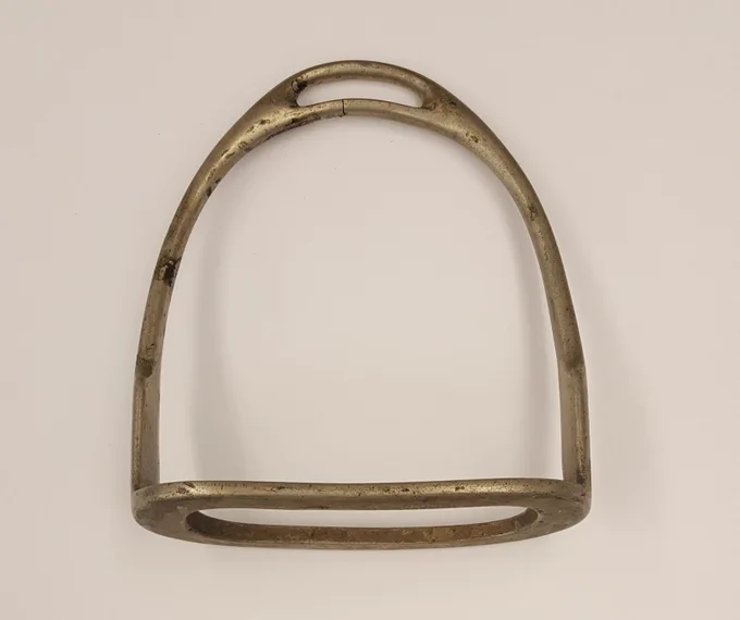 Metal horse stirrup with a simple, rounded design and a worn patina, from the Interior Museum's collection.