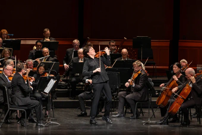 Violinist Joshua Bell playing a solo surrounded by New Jersey Symphony musicians.