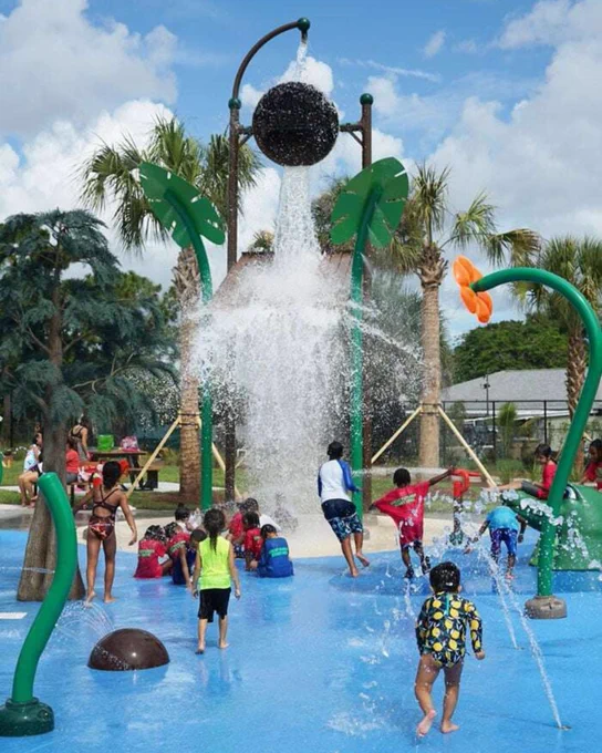 Lots of children playing in a splash park with sprayers and waterfalls