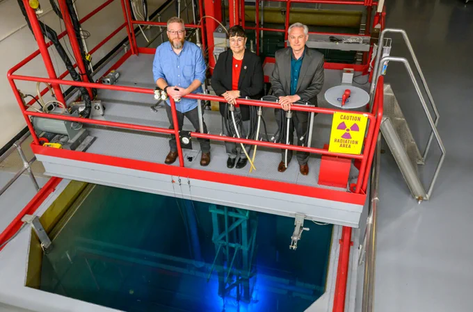 Color indoor photo of Corey Hines (left), Noel Schulz (center), and John McCloy stand above the research reactor at the WSU Nuclear Science Center (photo by Robert Hubner, WSU Photo Services).
