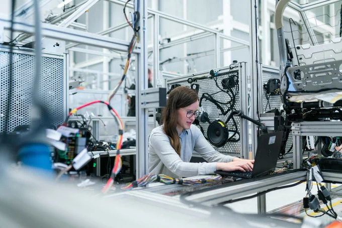 A person working on a laptop in an industrial technology setting.