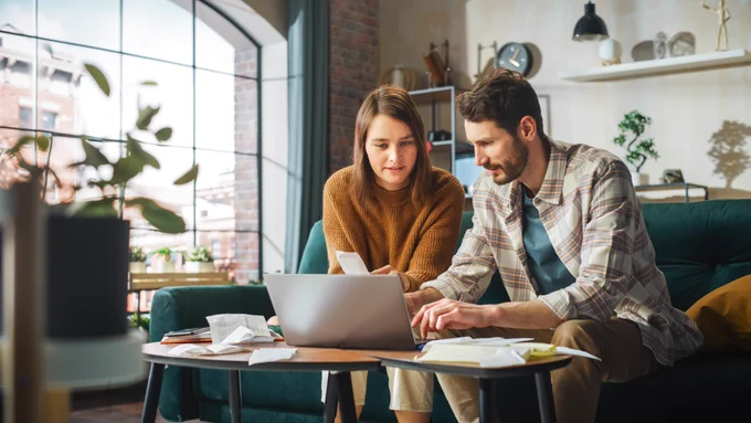 A couple sitting on the sofa working out their finances.