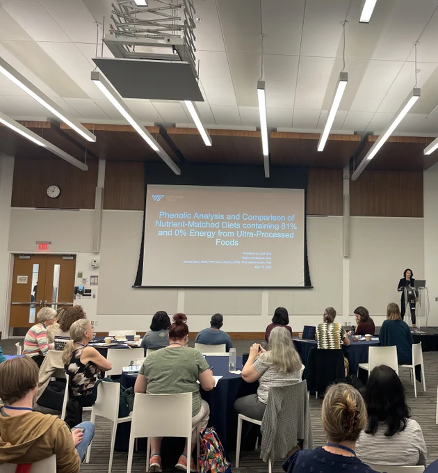 Graduate student Leah Ellis giving a presentation at the National Nutrient Database Conference. The slide reads: "Phenolic Analysis and Comparison of Nutrient-Matched Diets containing 81% and 0% Energy from Ultra-Processed Foods." 