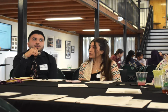 Two event attendees speak at a table.