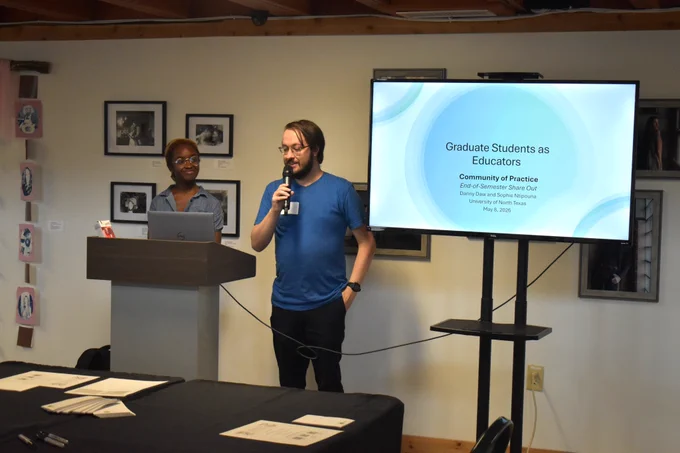 Community of practice co-leaders Sophie Ntipouna and Danny Daw present a slide deck behind a dais.