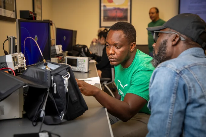 Ohio University students working in a lab with various technology equipment led by Professor Julio Aráuz, who stands in the background.