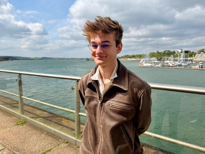 Young man with short brown hair stood by the sea