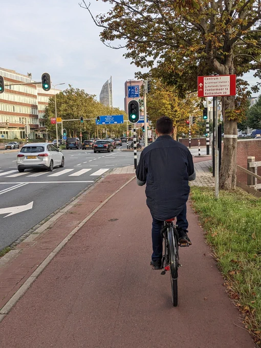 Junger Herr auf einem Fahrrad auf rot asphaltierter Radinfrastruktur in Den Haag