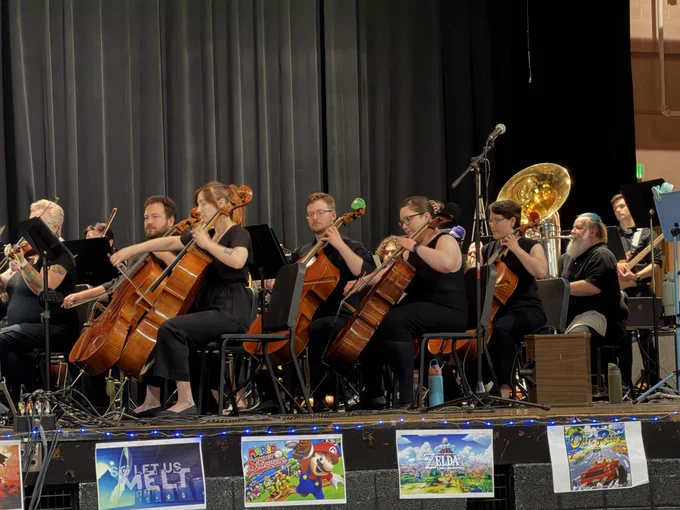 A section of the orchestra - strings and low brass - performing on stage