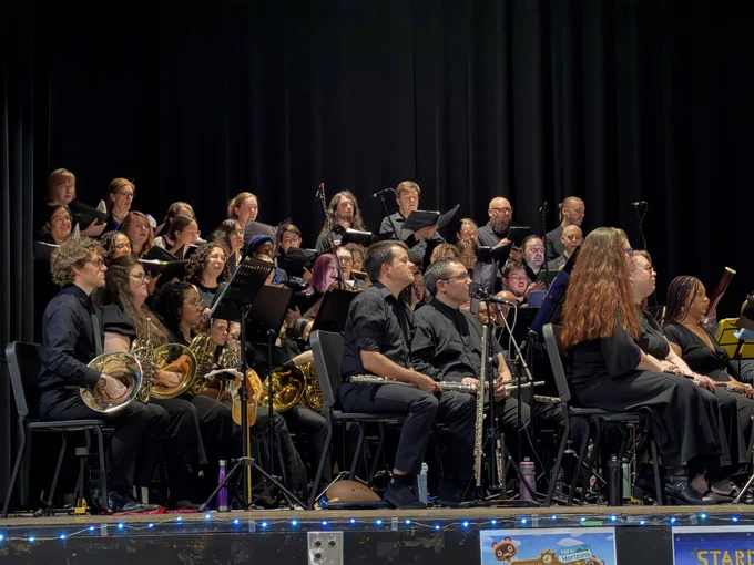 A section of the orchestra - choir, French horns, and flutes - performing on stage