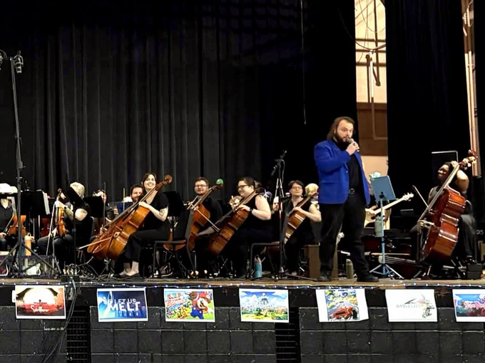 The orchestra preparing to perform a song as Tad introduces the next piece