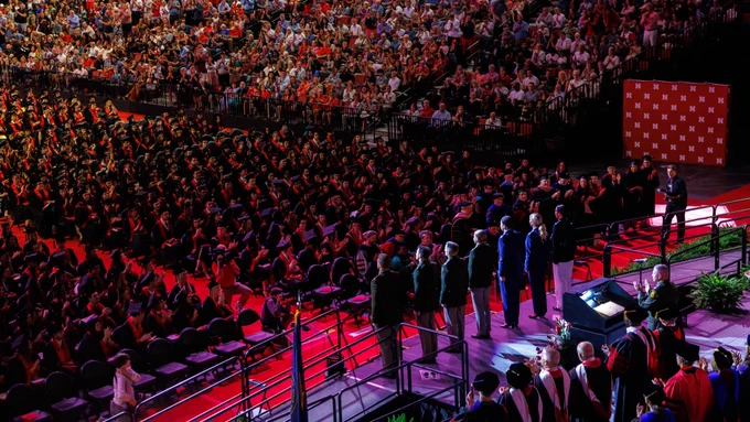 Seven ROTC members in uniform stand onstage at Pinnacle Bank Arena as the audience and their fellow graduates applaud. (Jordan Opp/University Communication and Marketing)