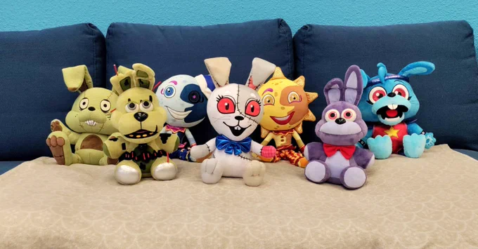 Sanshee plushies on a blue couch. Plushtrap, Springtrap, Moon, Vanny. Sun, Bonnie, Glamrock Bonnie