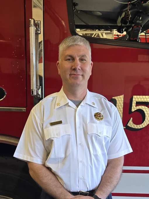 A photo of Deputy Chief Zaremba next to a fire engine.