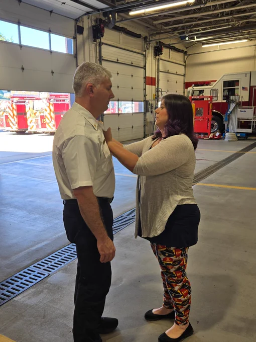 A photo of Deputy Chief Zaremba having his badge pinned on by his wife.
