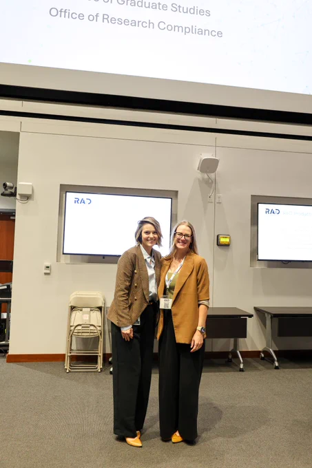 two people standing at presentation screen smiling arm and arm