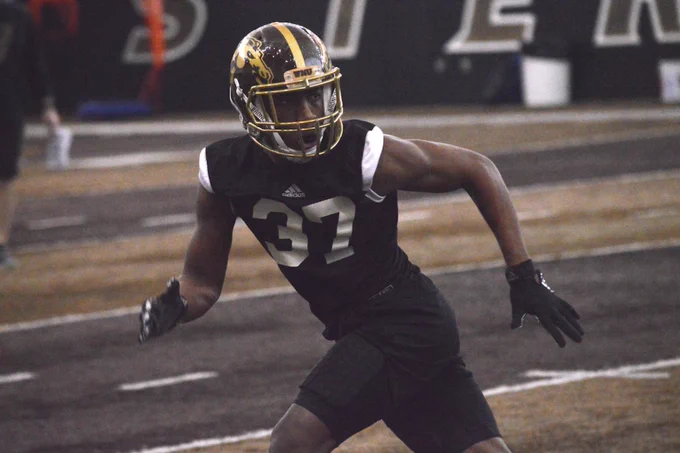 A football player wearing a Western Michigan University Broncos uniform with the number 37 is on the practice field, preparing to make a move.