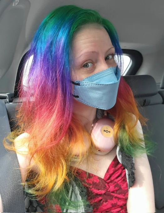 Lulu, with long rainbow hair, wearing a light blue k95 mask