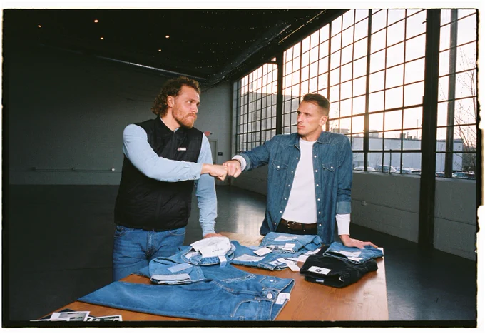 Brothers Jared and Joshua Ravenscraft fist-bumping over a pile of jeans
