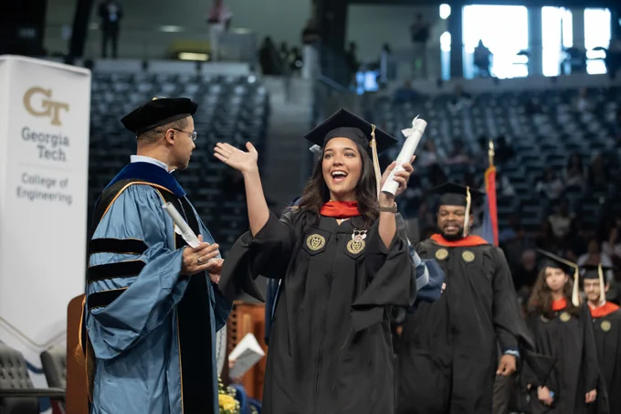 A graduate cheers as she walks across the stage.