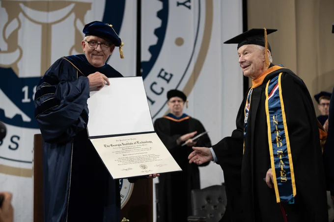 Kenneth Grundborg accepts his master's degree on stage from School of Civil and Environmental Engineering Chair Don Webster.