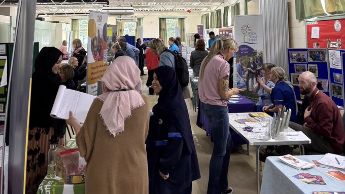People visiting information stalls and talking in a hall.  