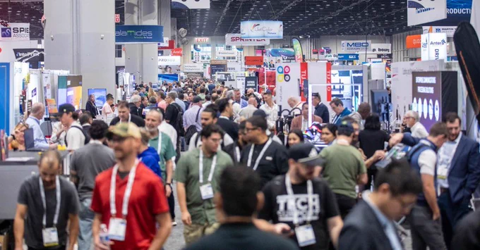 Crowded convention hall with numerous booths and attendees walking and exploring exhibits at the PRINTING United Expo.