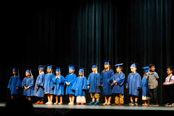 PreK graduates from ELC 1 lined up on stage dressed in their cap and gowns.