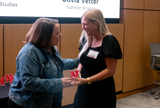 Allison Day smiles while accepting her Graduate with Distinction Award from AnnMarie Gottner