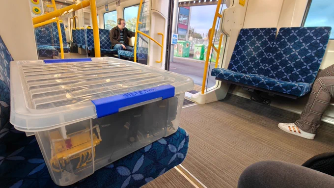 A Lego train packed in a container and placed on a train seat