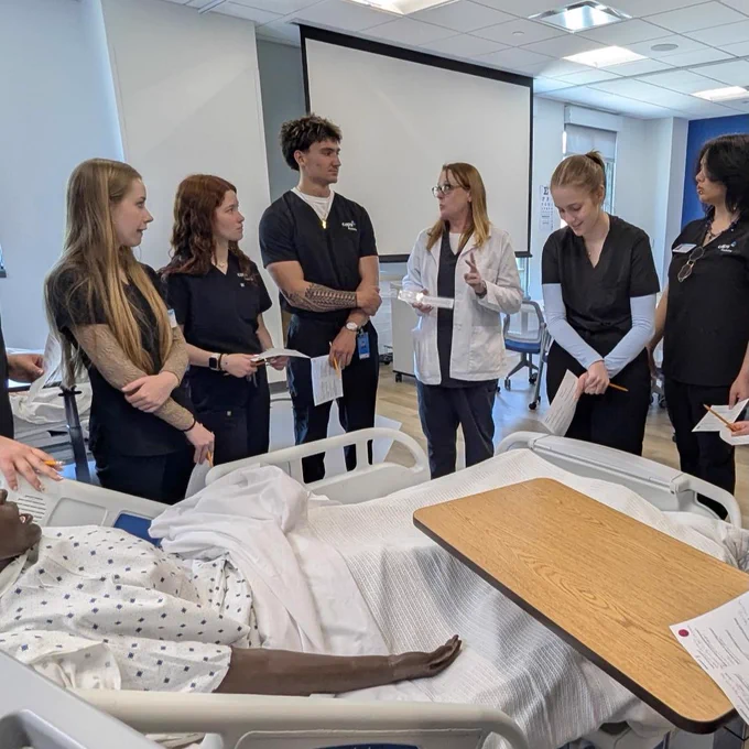 A group of healthcare professionals standing around a hospital bed, discussing patient care and procedures.