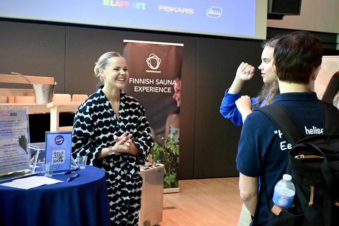 A woman in a bathrobe smiling and speaking to two people.