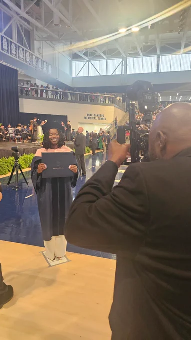 A female doctoral graduate poses for a photo with her degree cover.