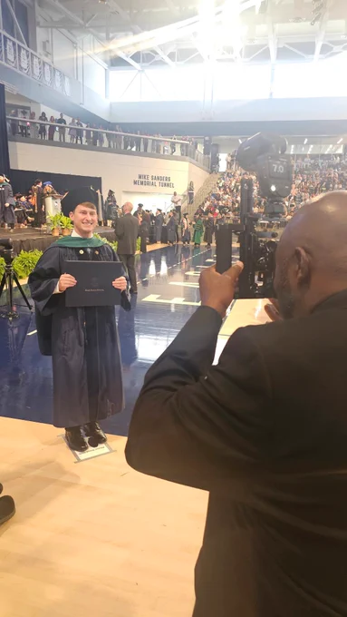 A male doctoral graduate poses for a photo with his degree cover.