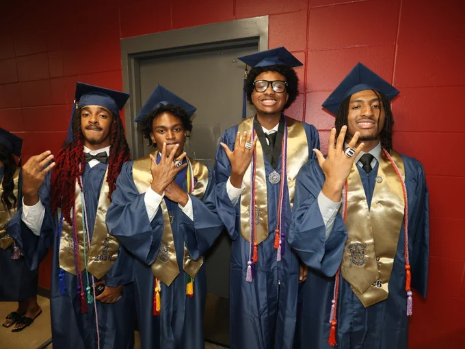 Students posing for camera at graduation ceremony.