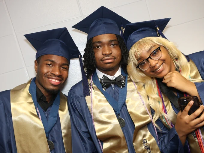 Students posing for camera at graduation ceremony.