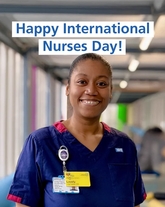 Nurse in navy blue NHS scrubs standing in a hospital corridor with a badge reading 'Lovely' and a stethoscope, celebrating International Nurses Day.