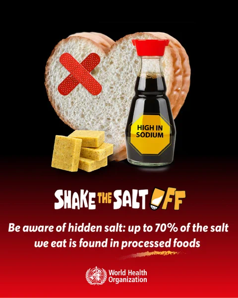 Heart-shaped bread with a red bandage and a soy sauce bottle labeled high in sodium beside bouillon cubes, highlighting hidden salt in processed foods.
