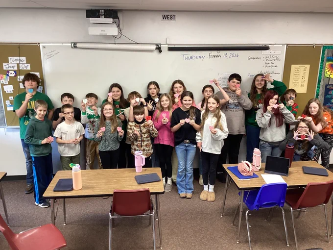 Mr. Miller's students pose in the front of a classroom, holding up 3D prints! 