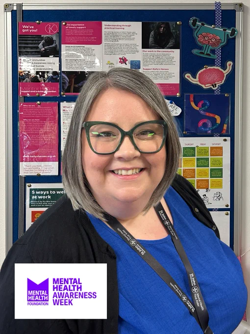 Window Ware's mental health first aider, Laura Hagger, posing before a noticeboard displaying various mental health posters and information during Mental Health Awareness Week.