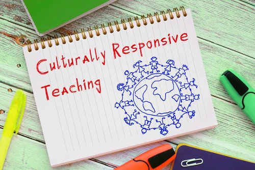 Notebook on table. “Culturally Responsive Teaching” with hand-drawn image of a globe with cartoon students holding hands around the globe.