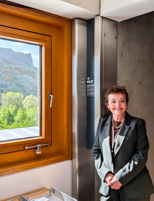 Heather Anderson MSP at her office in the Scottish Parliament with Salisbury Crags in the background.
