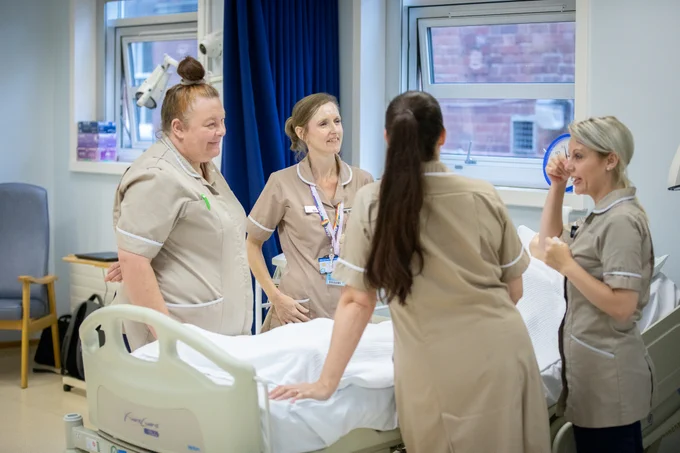 Four nursing associate students stood round a hospital bed