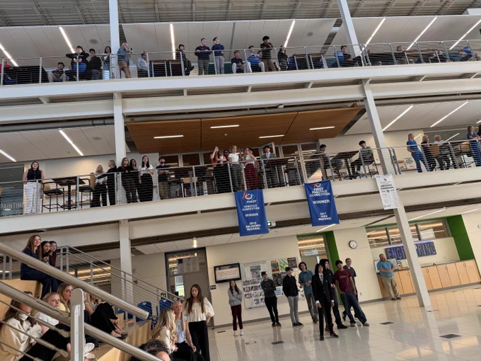A view of the CAPS atrium looking up at all levels, as students look down to main level video presentation.