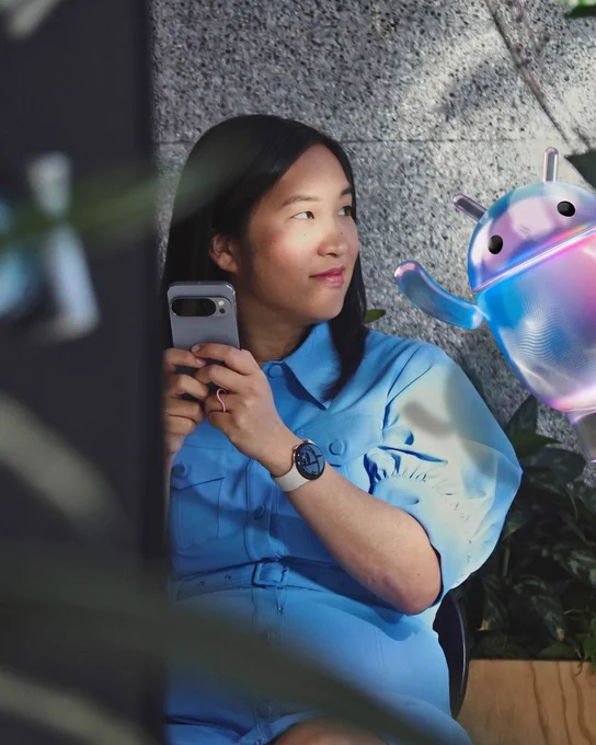 Person interacting with a holographic Android mascot on a phone.