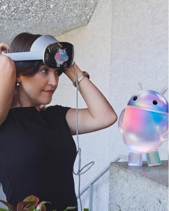 Person interacting with a virtual Android mascot in an XR headset.