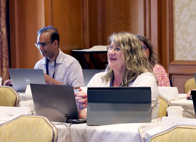 Person smiling in training session with two laptop screen